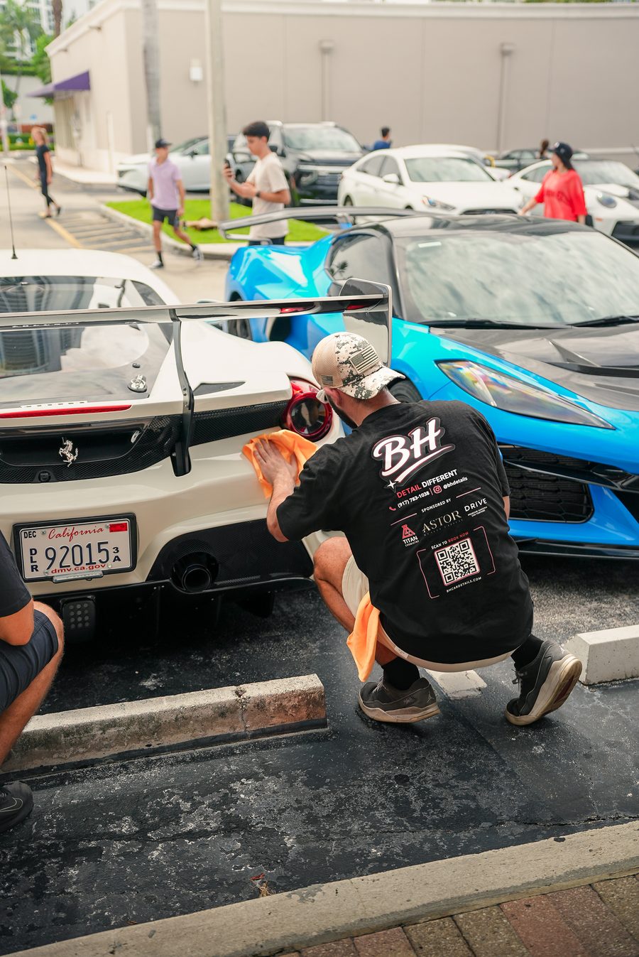 BH Car Detailing hand-finishing a widebody Ferrari trackday build beside a blue exotic